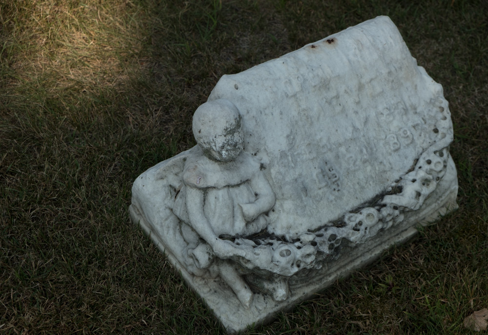 carved tombstone with a spot of sunlight